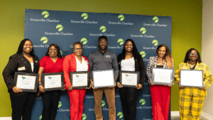 Minority Business Accelerator graduates holding certificates in front of a Greenville Chamber backdrop