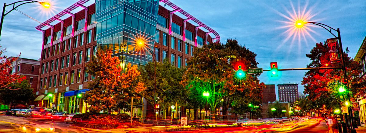 Downtown Greenville street with city lights at dusk