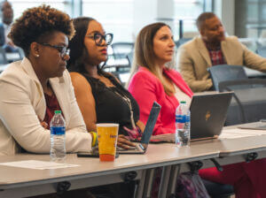 Program participants seated at a table with laptops during a session