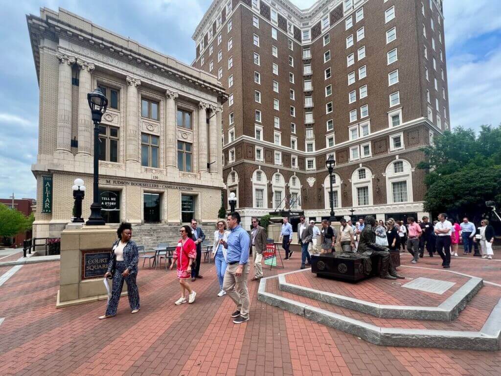 Pedestrians in a downtown plaza surrounded by historic buildings