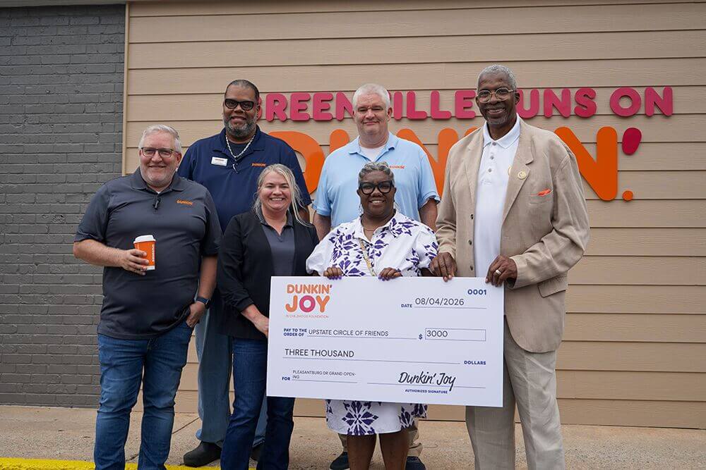 Bluemont Group and Dunkin' representatives presenting an oversized check outside a Dunkin' location