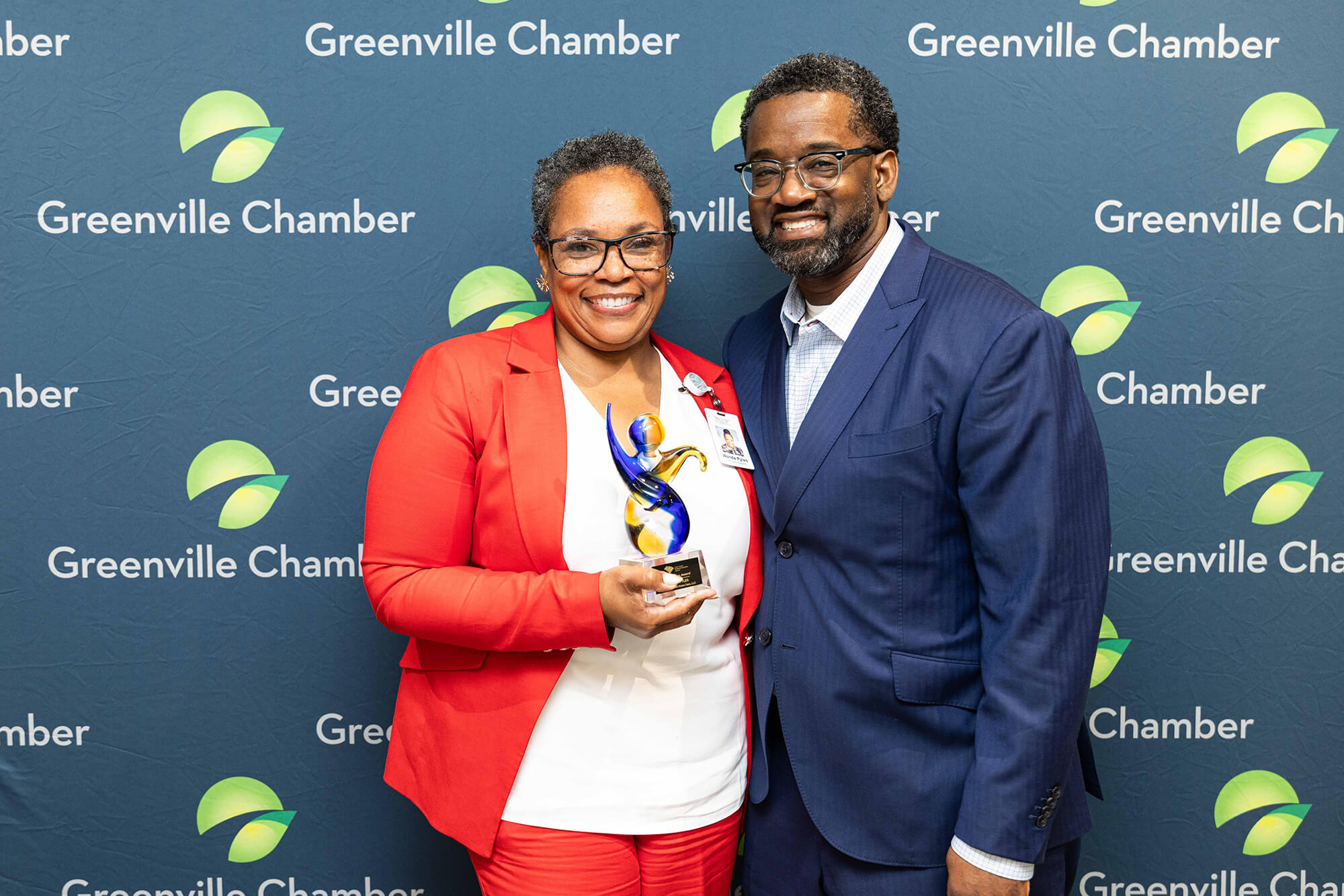 Award recipients posing with a trophy in front of a Greenville Chamber backdrop