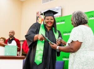Graduate in cap and gown receiving a certificate at a celebration