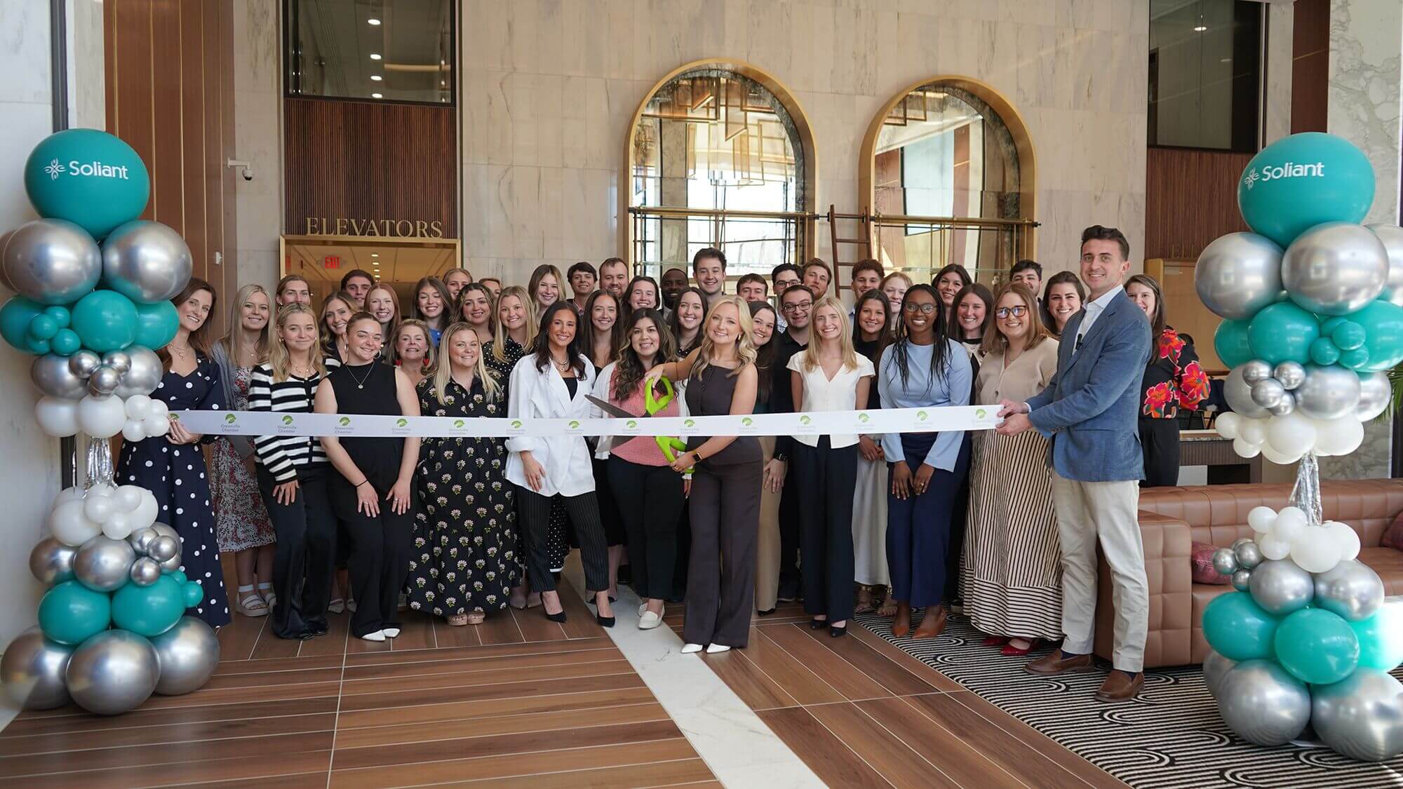 Ribbon cutting celebration with teal and silver balloons for Soliant