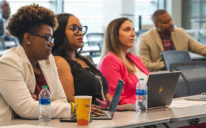 Program participants seated at a table with laptops during a session