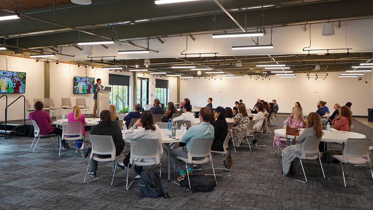 Attendees seated at round tables during a program in a large event room