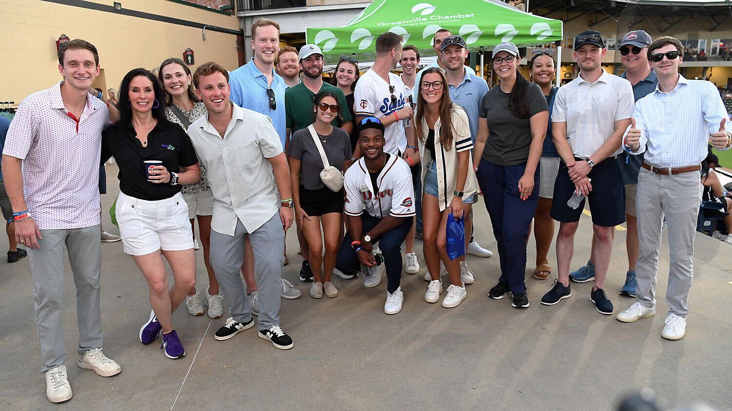 Group of attendees posing outdoors under green tents at a summer event