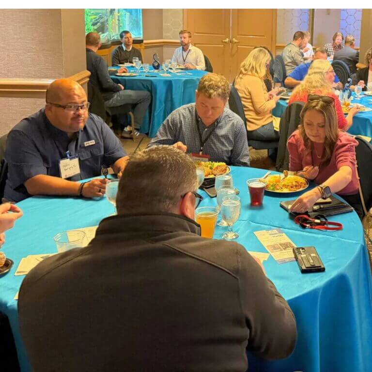 large group of people sitting around tables eating meal