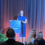 woman speaking at podium in front of group of people