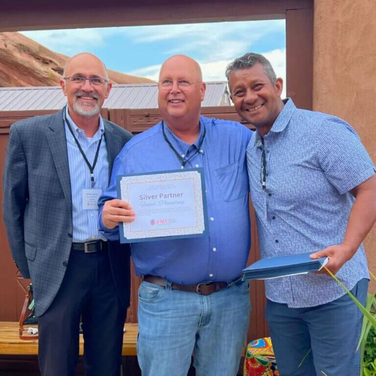 man receiving award with two men presenting