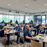 people sitting around tables watching presentation