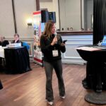 woman speaking into microphone in front of group of people