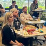 people sitting around tables watching presentation