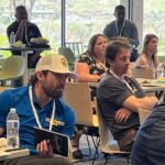 people sitting around tables watching presentation
