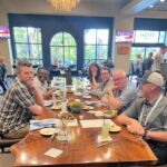 six people sitting around a table eating meal
