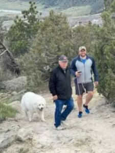 two men and a dog on hiking trail