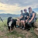 group of people with a dog sitting on log bench