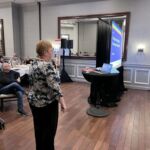 woman speaking at event with people in background sitting at tables