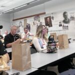 people with bag lunches sitting at tables listening to presentation
