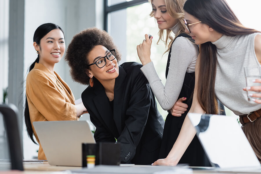 african american businesswoman smiling near multiethnic colleagu business women smiling