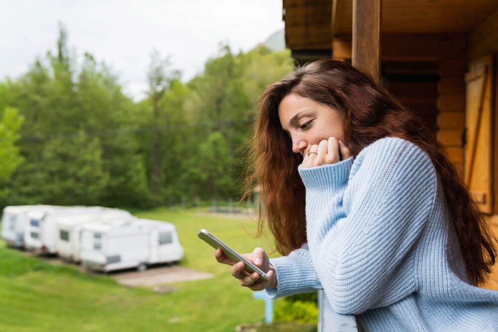 vecteezy_pensive-woman-browsing resized Woman browsing on cell phone with RVs in background