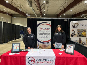 Volunteer Manitoba team members standing at a booth