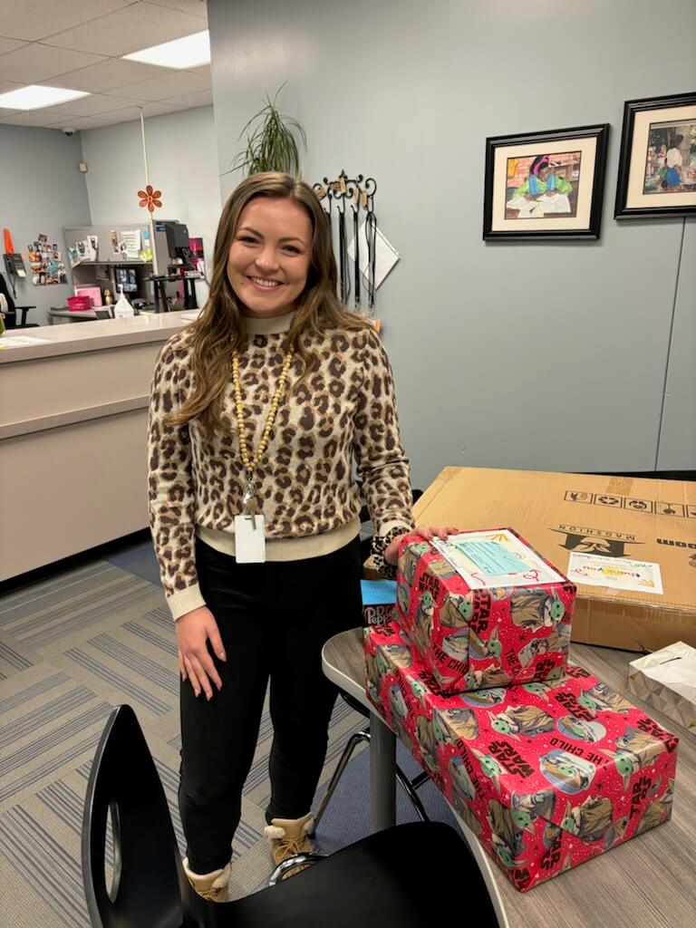 A smiling teacher holding gifts.