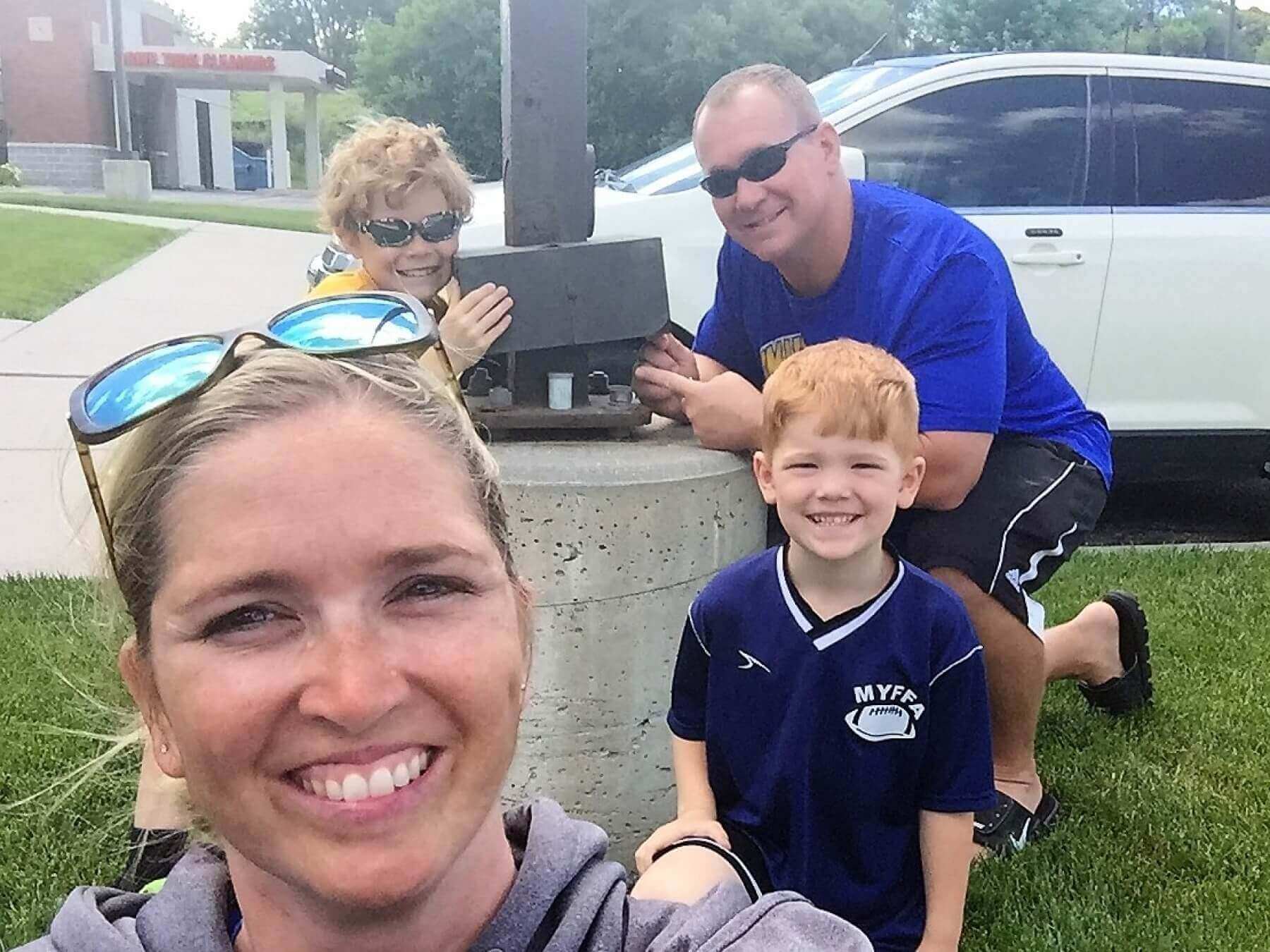 family selfie in front of a car
