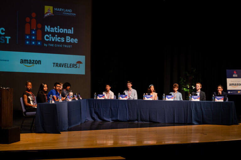 A group of eleven middle school students from across the state of Maryland are seated on a stage during the 2023 National Civics Bee for Maryland. Each of the students was a finalist in the annual civics bee competition.
