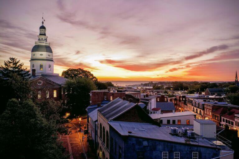 Aerial view of downtown Annapolis, Maryland at sunrise with the State House dome in foreground and Chesapeake Bay in background.