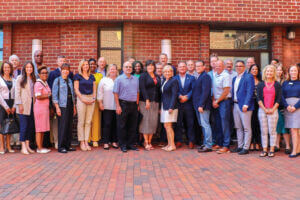 A large group including members of the Maryland Chamber of Commerce Board of Directors and organization staff gathered in front of brick building.
