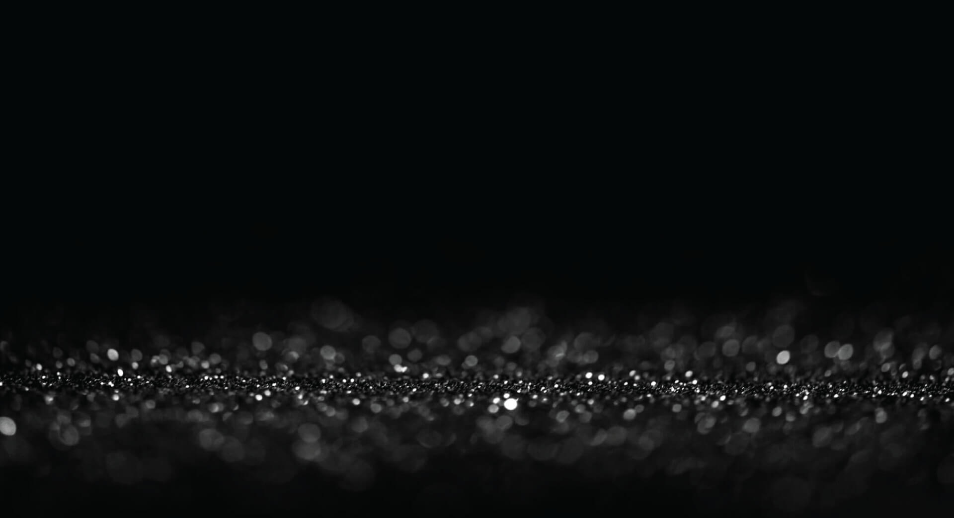 A black background graphic featuring clusters of silver speckles of confetti.