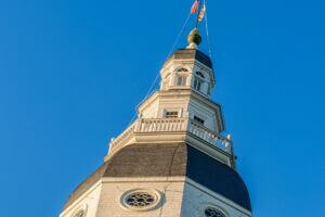 Looking up at an angle to top of Maryland State House dome against a blue sky on a sunny evening