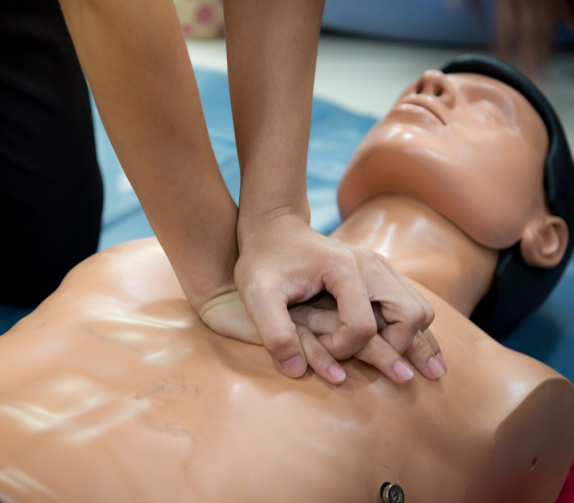 CPR training medical procedure - Demonstrating chest compressions on CPR doll in the class