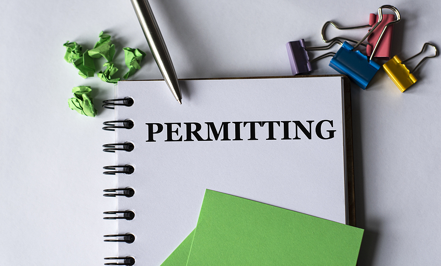 Permitting - Word In A Notebook On A White Background With A Pen PERMITTING - word in a notebook on a white background with a pen, green pieces of paper and a cactus. Business and education concept