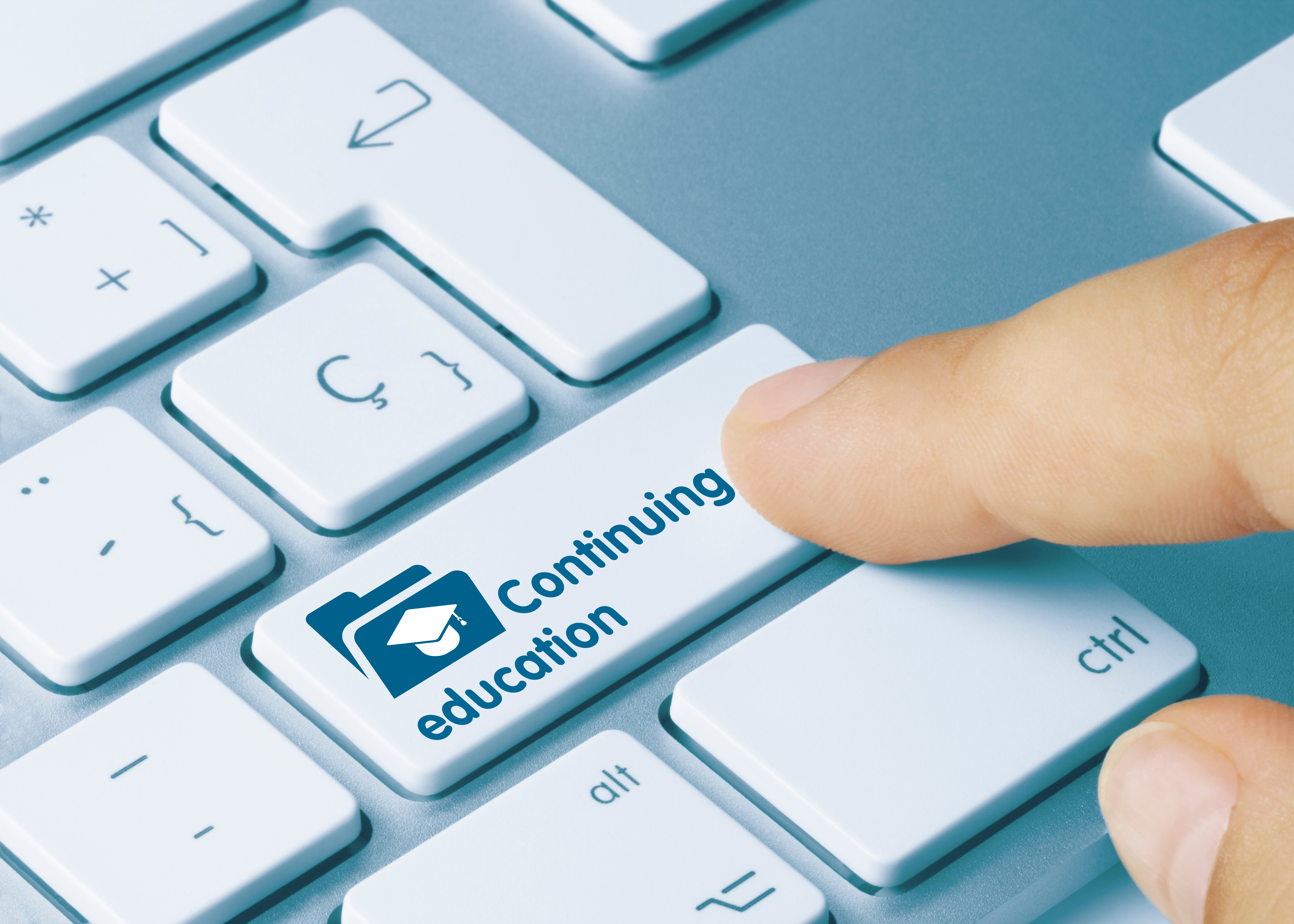 Continuing education - Inscription on Blue Keyboard Key. Continuing education Written on Blue Key of Metallic Keyboard. Finger pressing key.