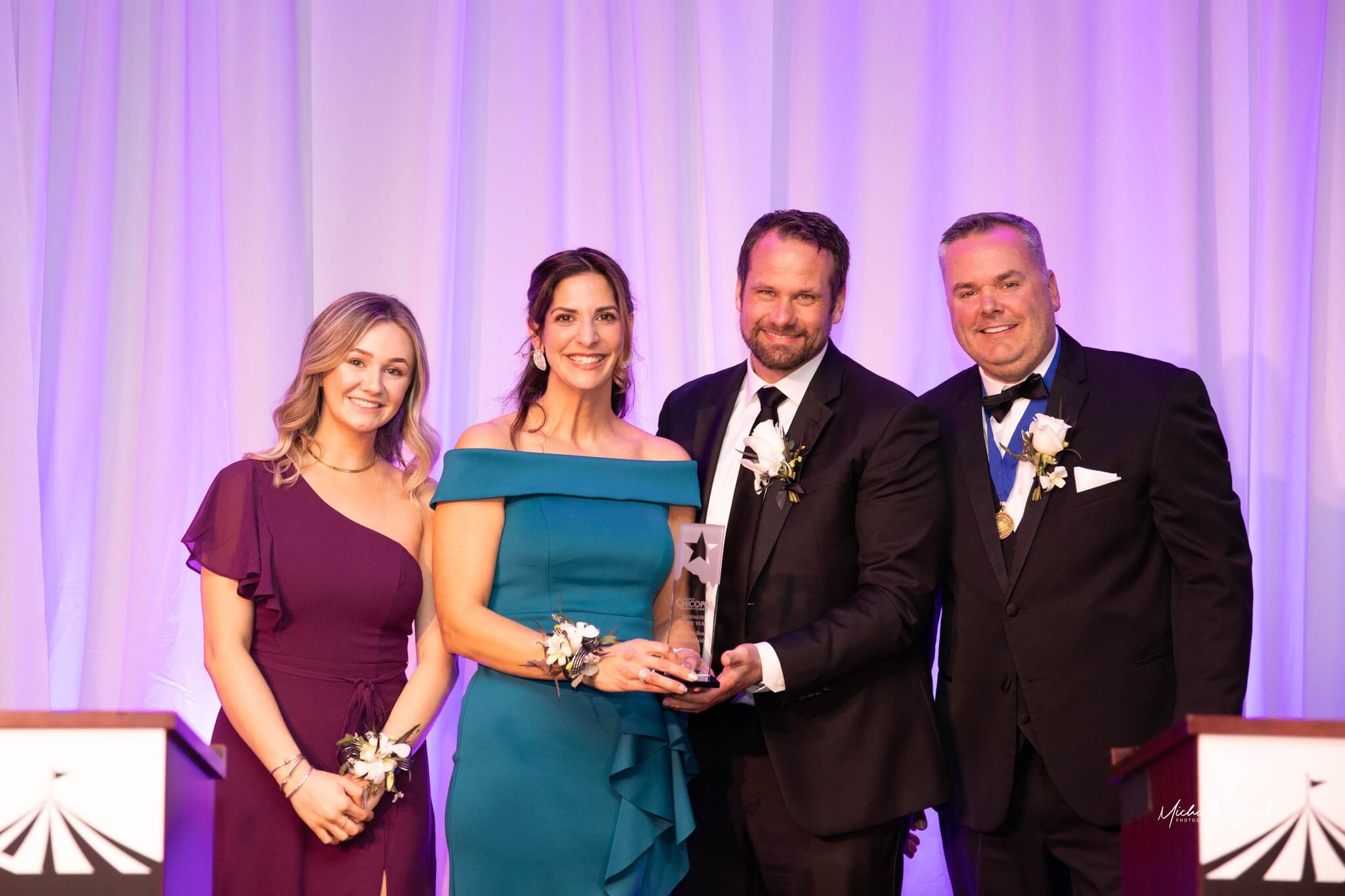 Mercedes-Benz of Springfield, accepting the Business of the Year Award, of the Year award, with Emcees Jeremy Procon and Haley Procon.