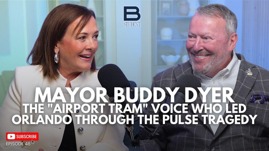 Chamber president/CEO Betsy Gardner, a woman with brown hair in a white jacket, sits besides Orlando Mayor Buddy Dyer, a man with salt and pepper hair and beard in a plaid suit jacket and white shirt.