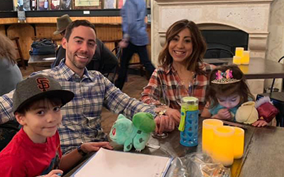 family at table waiting for their food and smiling at camera