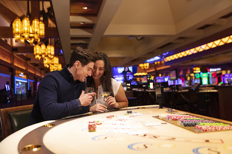 couple at black jack table at casino having a beverage