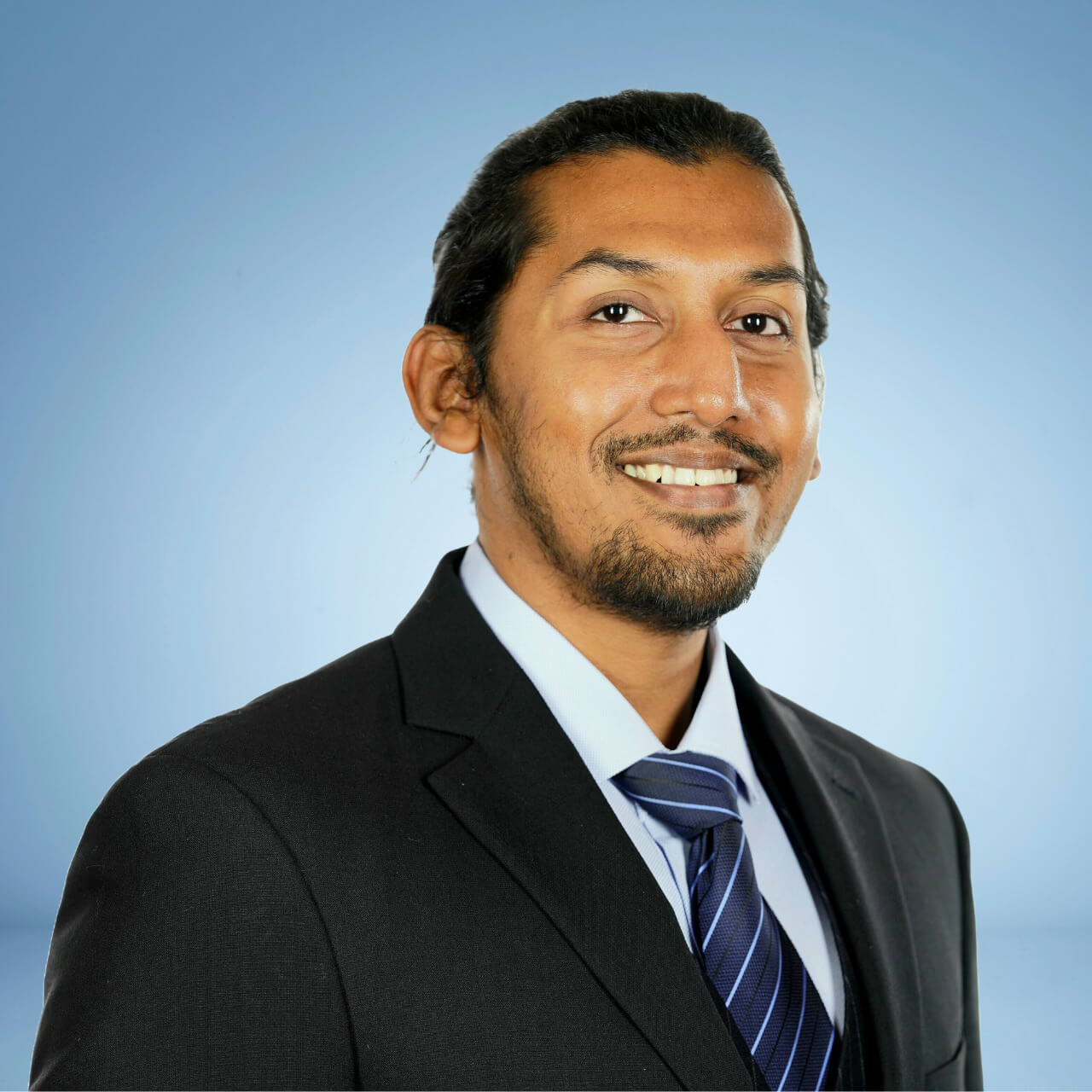 Salman headshot small Salman bin Habib headshot. He is wearing a black blazer, blue striped tie, and a white button down.