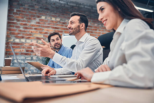 Young smiling colleagues sitting in modern office at desk with computers