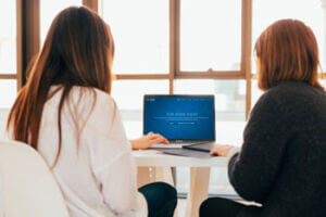 two people photographed from the back working on a laptop computer