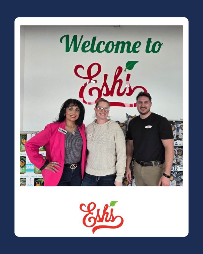 Two women and a man standing in front of a sign that says Welcome to Esh's