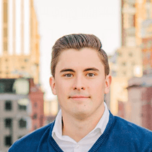 Headshot of a man with a city background.