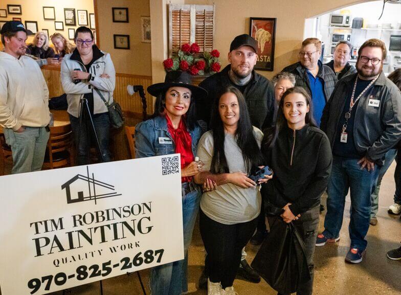 People standing together smiling with a sign that says Tim Robinson Painting.