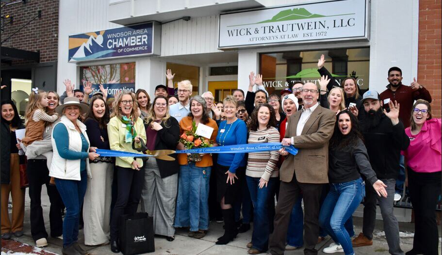 Large group cheering behind a ribbon with giant scissors