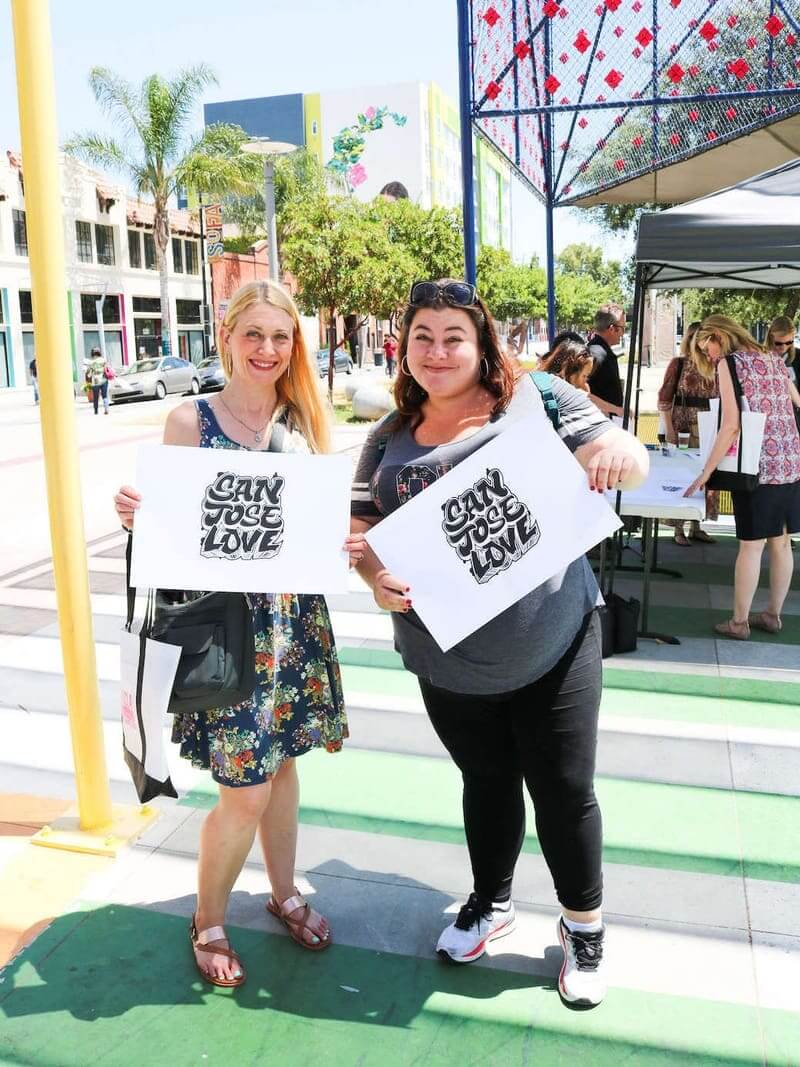 2 women holding signs with QR codes on them