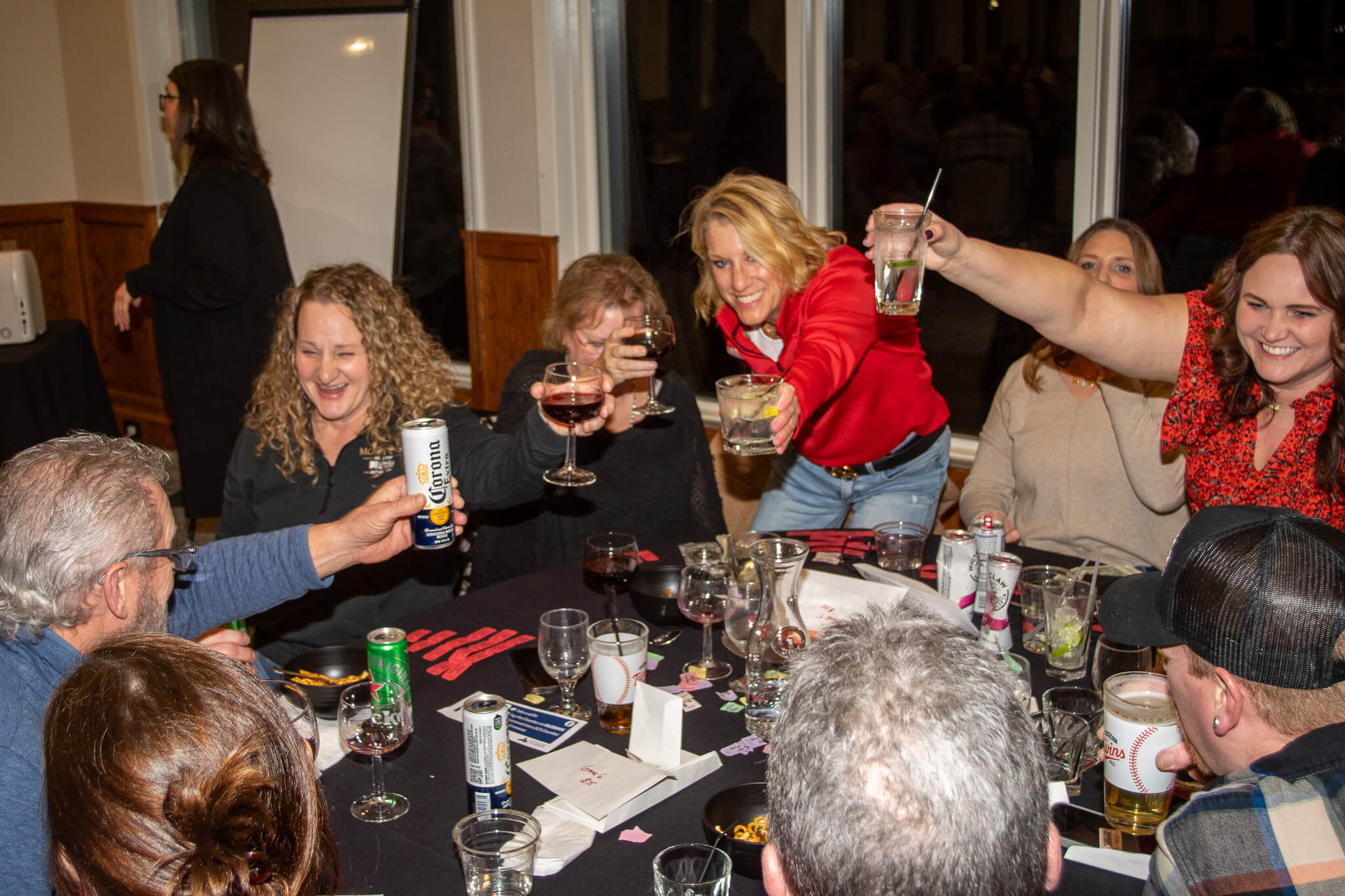 A group of people raising their glasses to the center of a table while smiling.