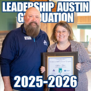 The President and CEO of the Austin Area Chamber of Commerce standing next to a Leadership Austin cohort student, Anna Good, at the graduation ceremony while holding a certificate of achievement.